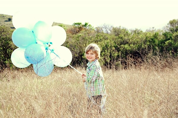 Niño pequeño en el campo con globos