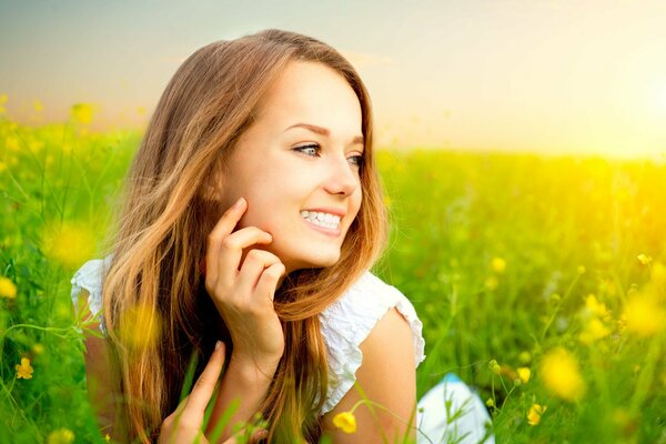 Ein Mädchen in einem weißen Sommerkleid liegt mit einem Lächeln im Gesicht im Sonnenlicht
