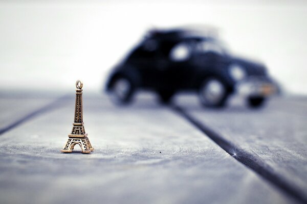 A small Eiffel Tower on the background of a blurry car