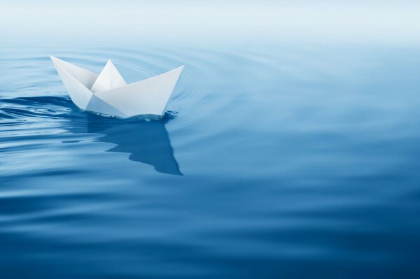 Un valiente barco de papel flotando en las olas azules
