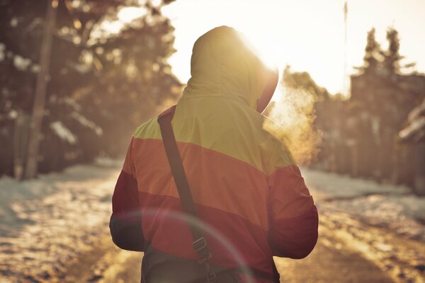 The guy walks down the road with his back to the camera. The guy in the winter forest