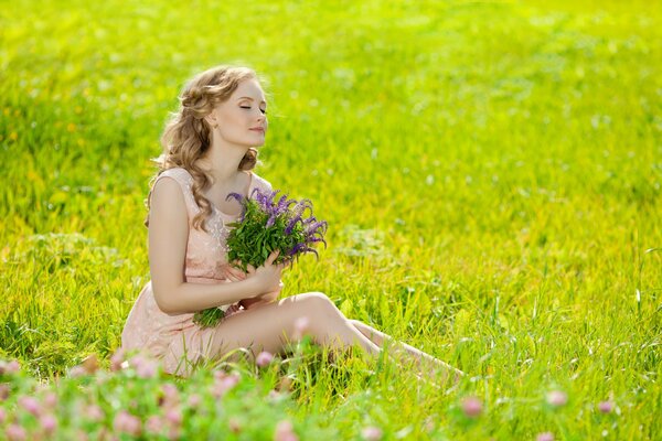 Blondine mit einem Blumenstrauß aus Wildblumen sitzt auf einer Lichtung