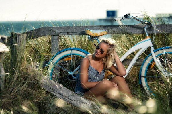 Chica sentada junto a una bicicleta en un Prado