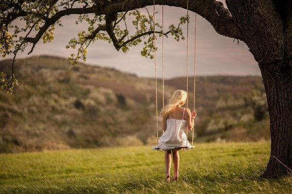 A girl is sitting on a swing