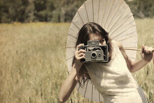 Ragazza in abito bianco con ombrello e macchina fotografica