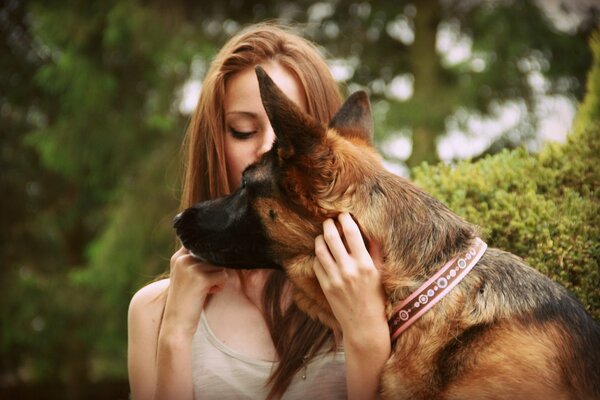 A girl with her eyes closed hugs a German shepherd