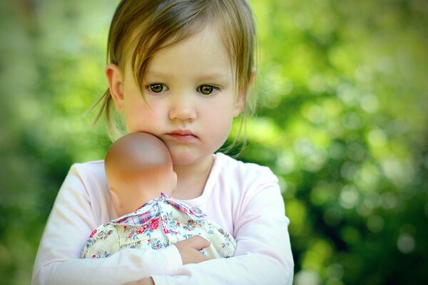 Kleines trauriges Mädchen umarmt eine Puppe