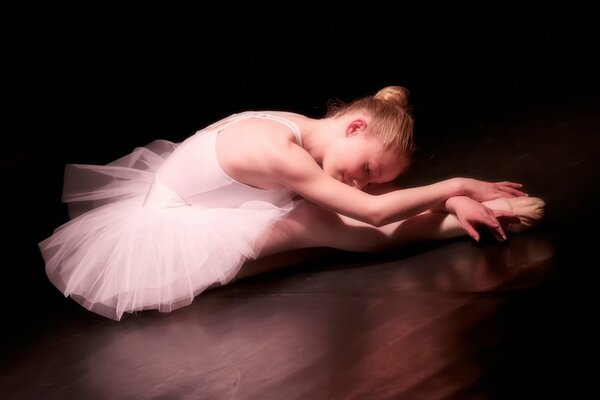 Девочка балерина делает растяжку в пачке и пуантах