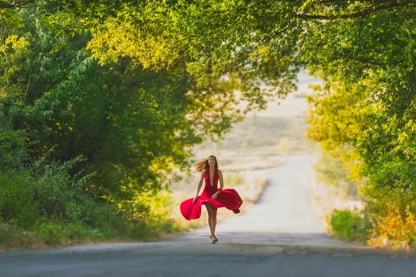 Ein Mädchen im roten Kleid geht die Straße entlang