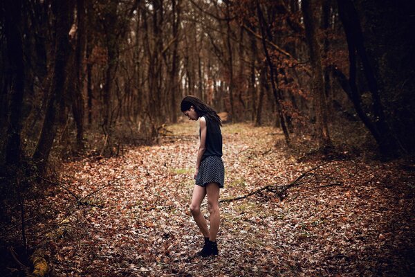 Dziewczyna w krótkiej spódniczce jesienią w lesie na drodze