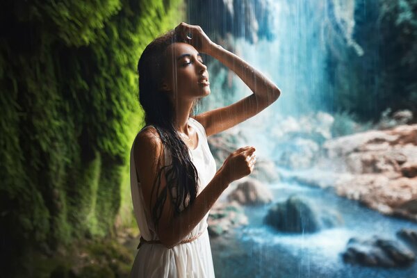 Fille en robe se tient à côté de la cascade