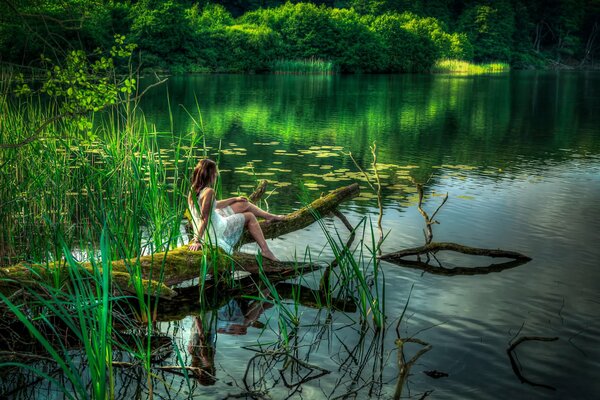 Forest, lake. A girl bathes her legs