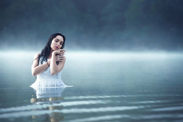 Foto di una ragazza in un lago nebbioso