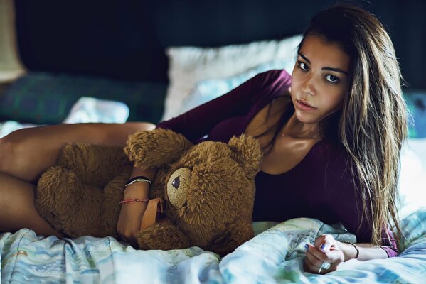 Mädchen liegt mit einem Teddybär auf dem Bett