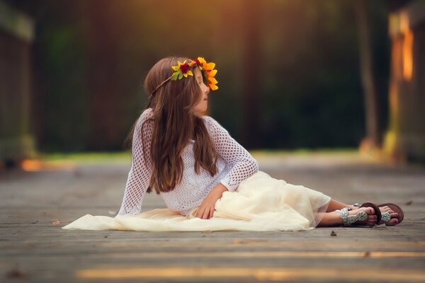 A child with a wreath is sitting on a wooden covering