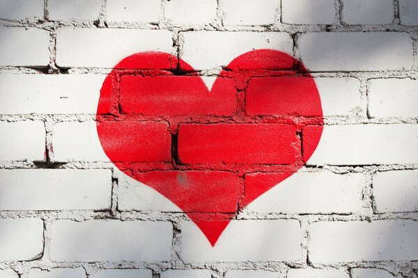 Red heart on a brick wall on a full-screen background