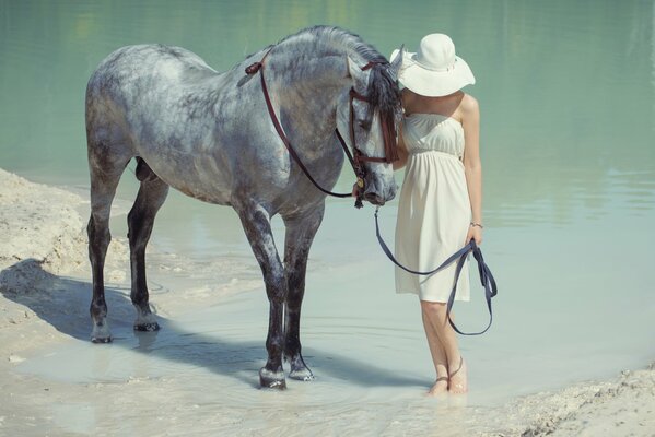 A girl in a hat walks a horse