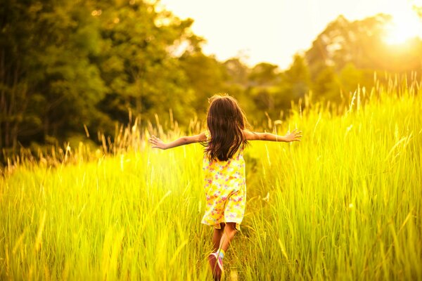 Una niña corre por el campo a la luz del sol