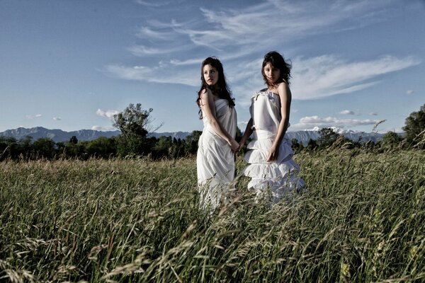 Girls in white dresses in a green field