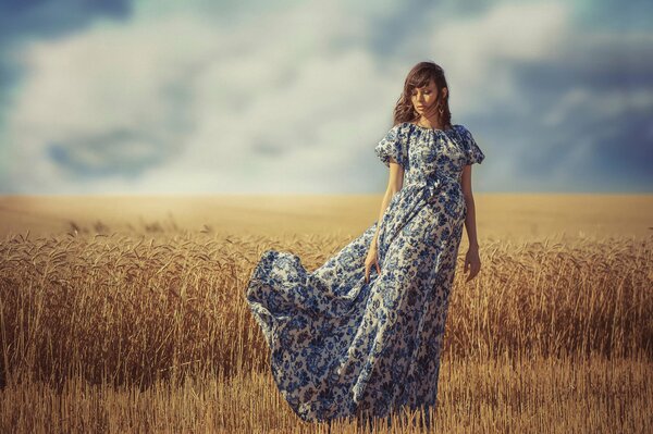 Una chica con un vestido revoloteando está de pie en el campo