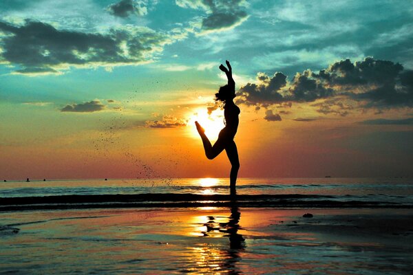 On the beach, a joyful girl runs in silhouette