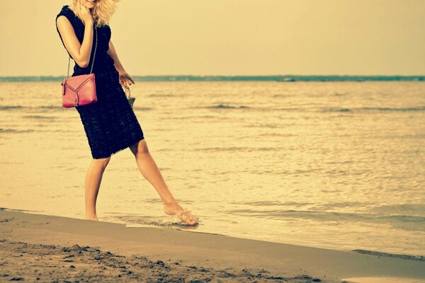 Passeggiata ragazza bionda sulla sabbia del mare