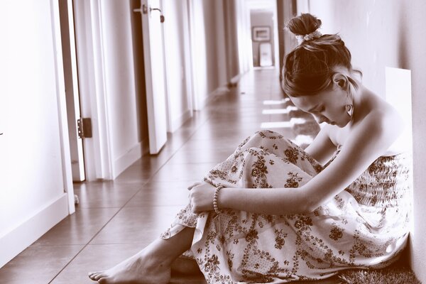 Monochrome photo of a sad girl sitting in an empty corridor