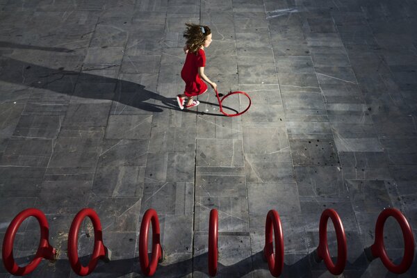 A girl in a red dress runs after a circle