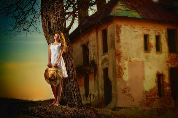 A barefoot girl stands at an abandoned house