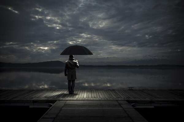 A man with an umbrella on the pier