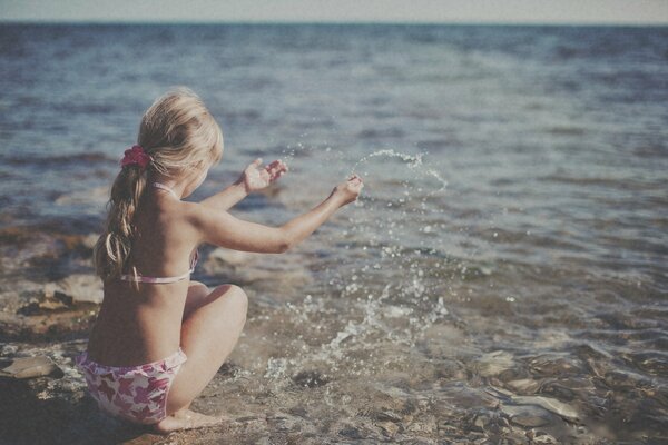 A girl on the seashore rejoices in the summer, the sun