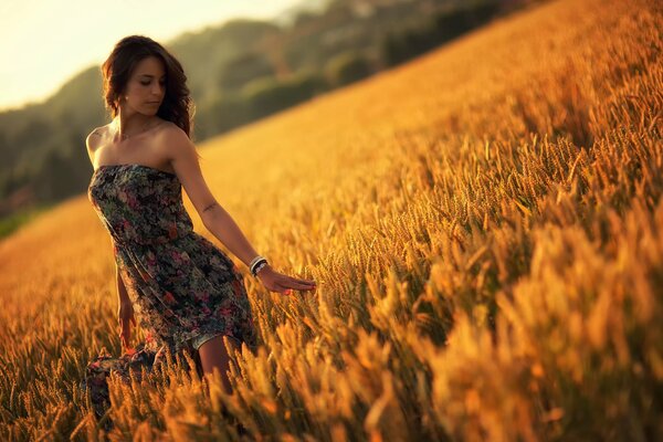 A girl in a summer dress in a wheat field