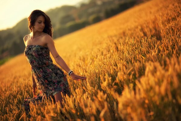 Una chica con un vestido de verano en un campo de trigo