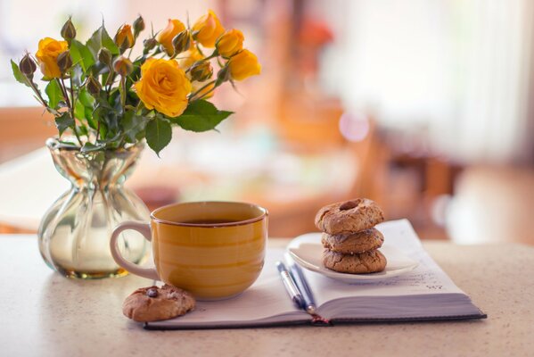 Stillleben Vase Blumenstrauß gelbe Rosen Tasse Tee Kekse