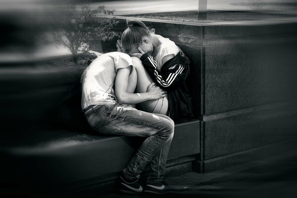 A young guy and a girl are sitting in an embrace