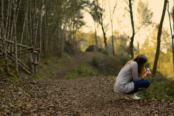 A girl is sitting on a forest path