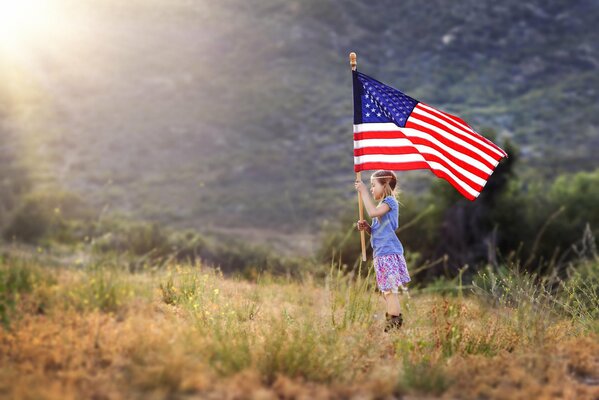 Маленькая девочка в поле с американским флагом