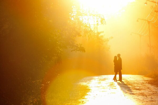 Una pareja de pie en la carretera en el sol de la puesta de sol