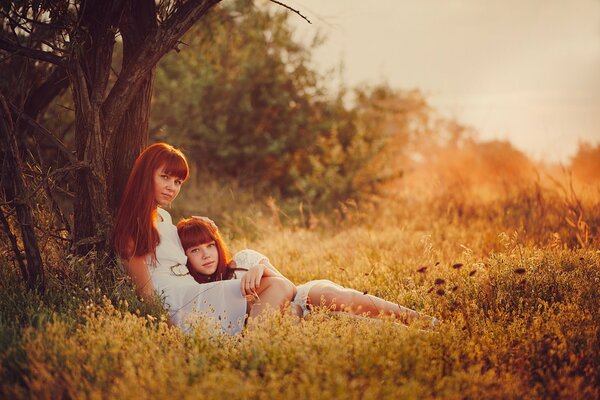 Mama i córka jak bliźniaczki pod drzewem na łonie natury