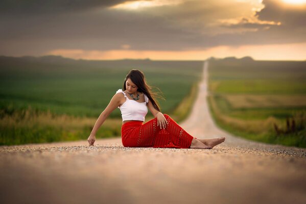 Ragazza in gonna rossa si siede sulla strada