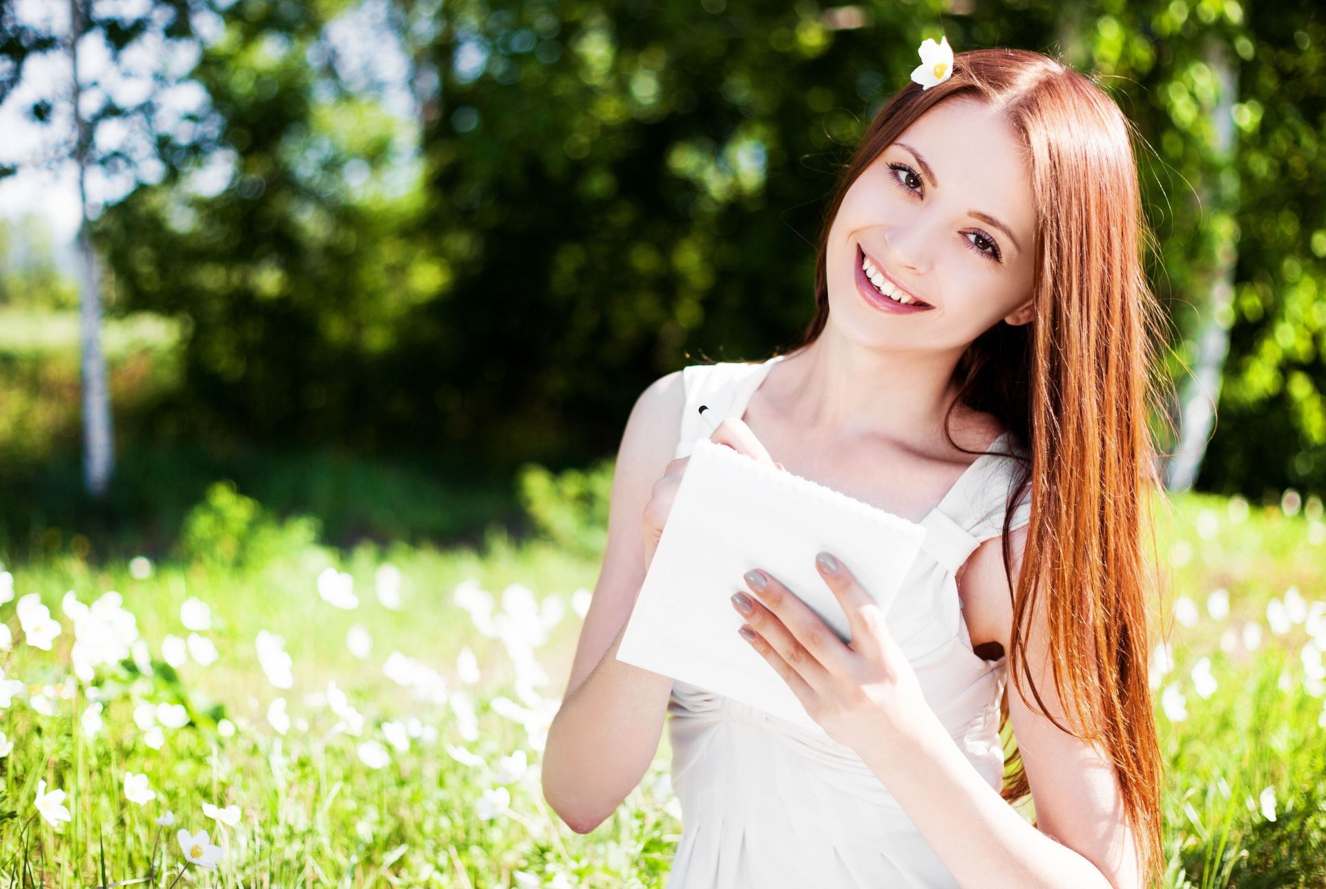 humeur fille rousse sourire regard mains. papier bloc-notes feuille nature champ fleurs fleurs soleil flou fond papier peint écran large plein écran écran large écran large