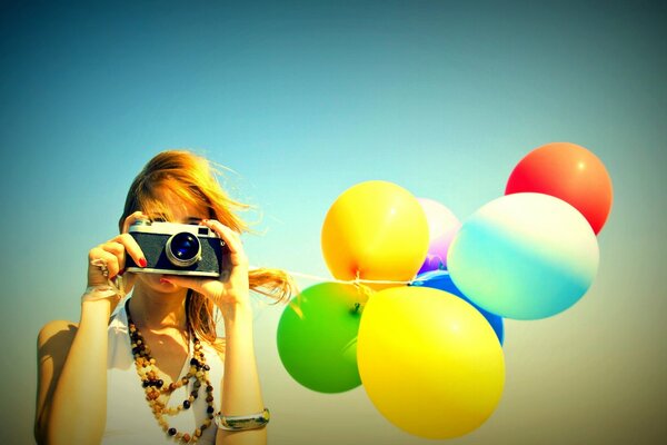 Fille avec un appareil photo et des ballons lumineux