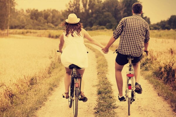 A guy and a girl ride a bike holding hands