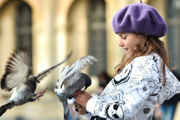 Dziewczynka w czapce karmi gołębie
