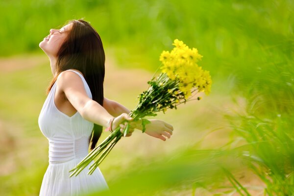 A girl in the field collects flowers for the comfort of home