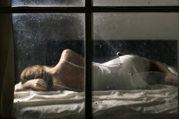Dziewczyna leżąca na łóżku z widokiem przez okno
