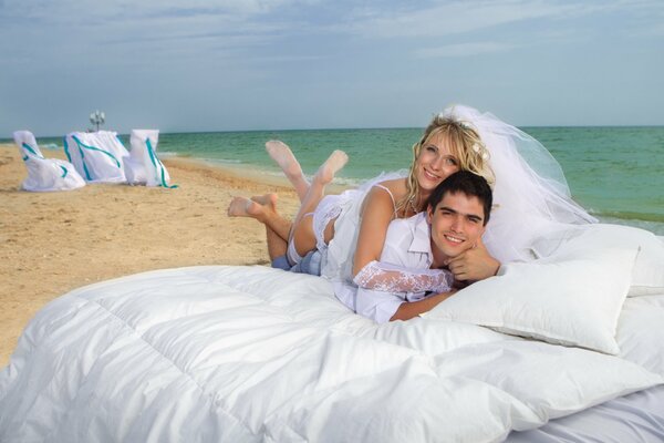 Mariée et le marié au lit sur la plage