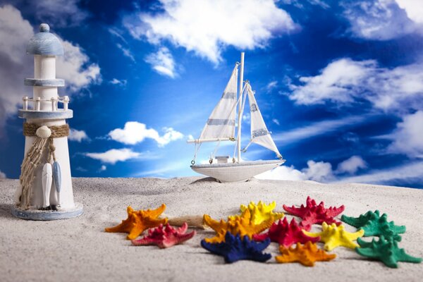 A model of a lighthouse and a ship on the sand against the sky