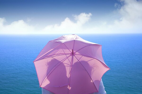 A couple in love hiding from the blazing sun under an umbrella