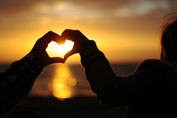 Lovers hands on the background of the setting sun